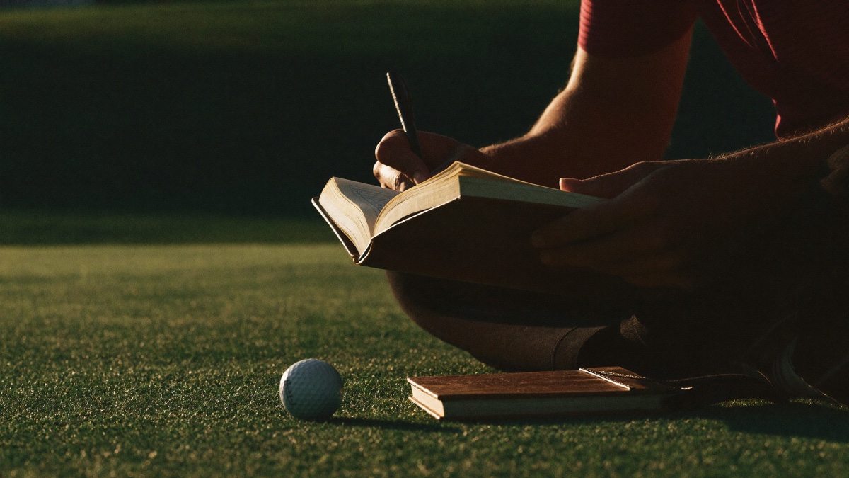 A golfer noting stats in a leather yardage book