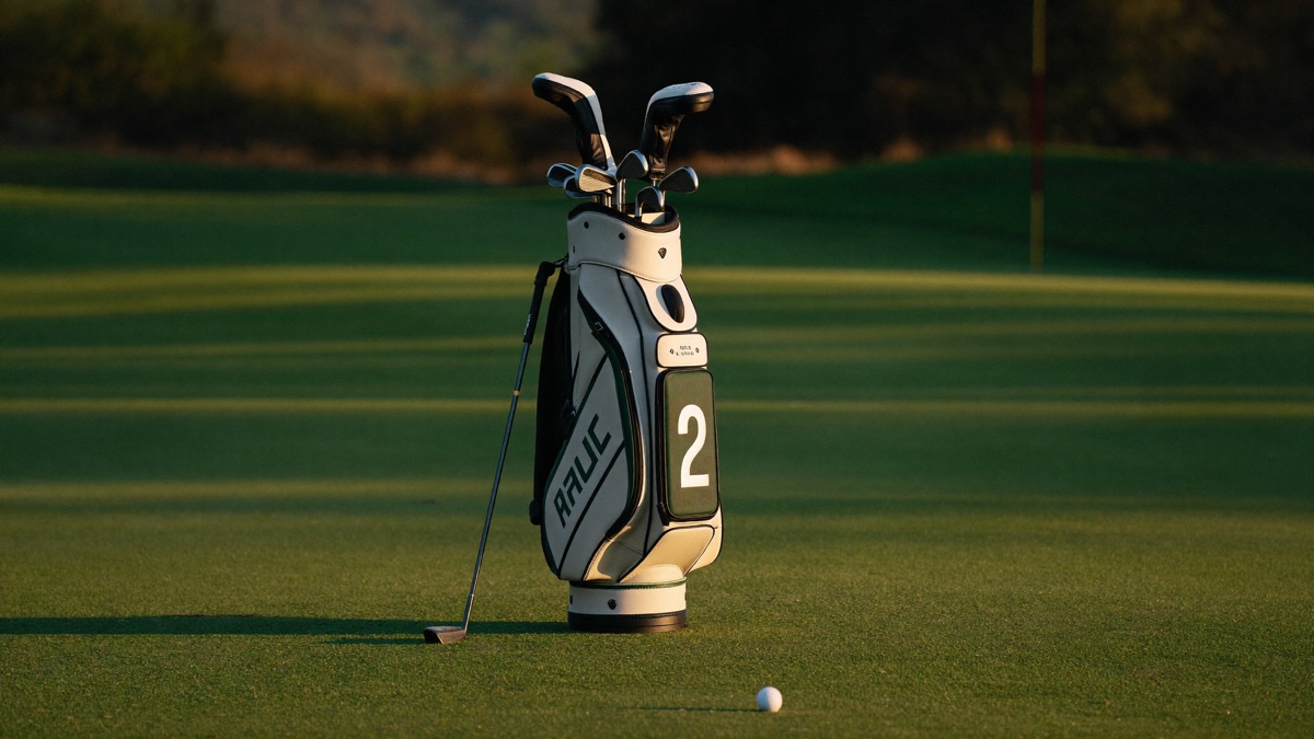 A golf bag holding only a driver, a putter, and wedges on a green at golden hour