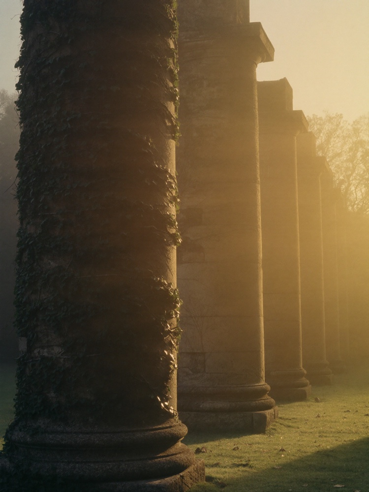A row of ancient stone columns at golden hour — the 9 Pillars framework Elite Golf Consulting is built on