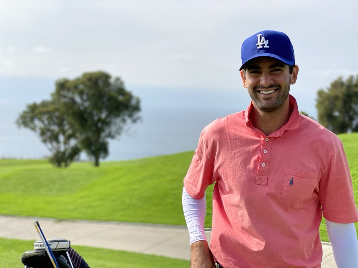 Matt Siporin smiling on a coastal golf course, golf bag beside him, ocean and green fairway behind
